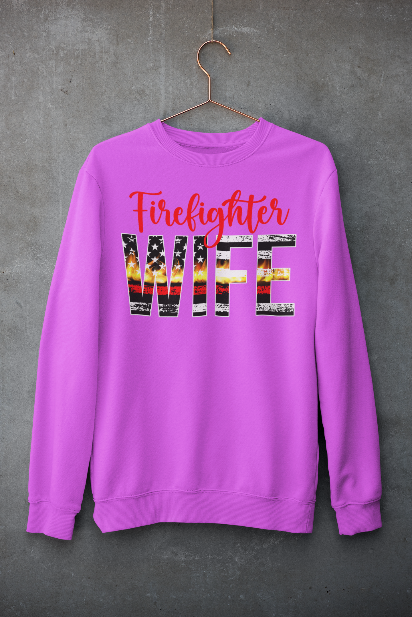 Pink sweatshirt with 'Firefighter WIFE' text on a hanger against a gray background