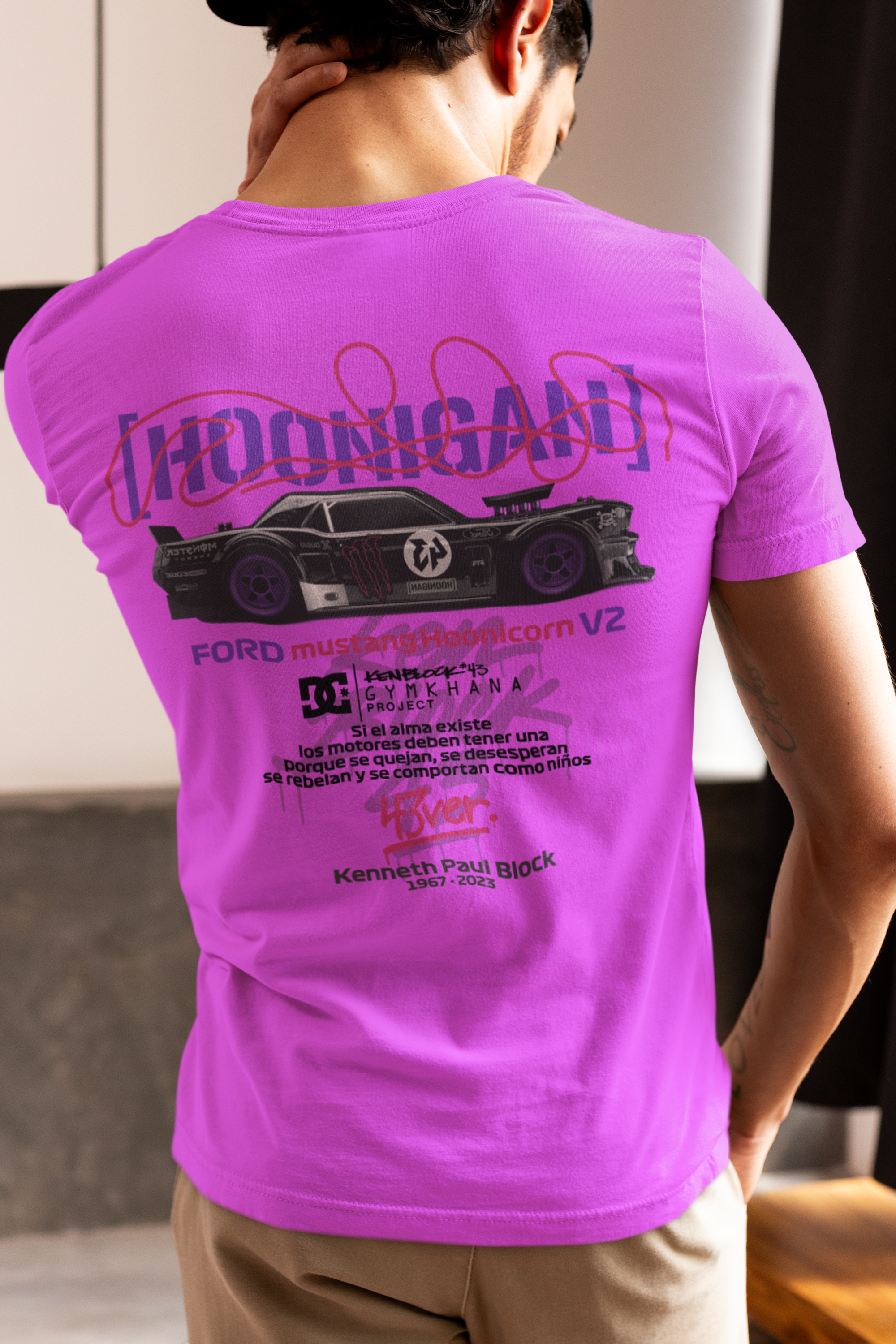 Person wearing a pink t-shirt with a graphic design on the back, standing indoors.