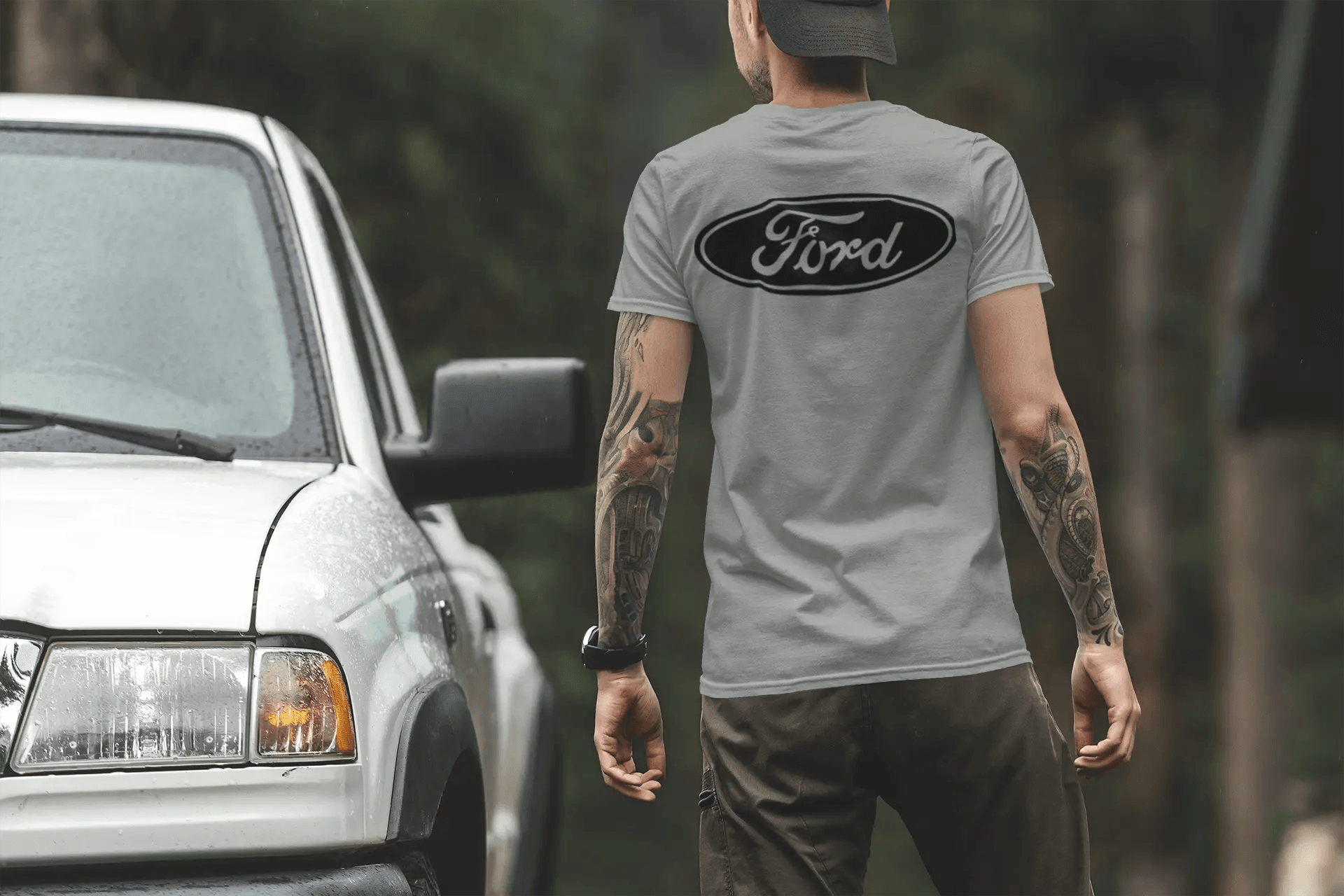 Person wearing a gray Ford t-shirt standing next to a white truck with a blurred background
