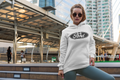 Woman wearing a hoodie with a Ford logo in an urban setting. gildan 18500 white
