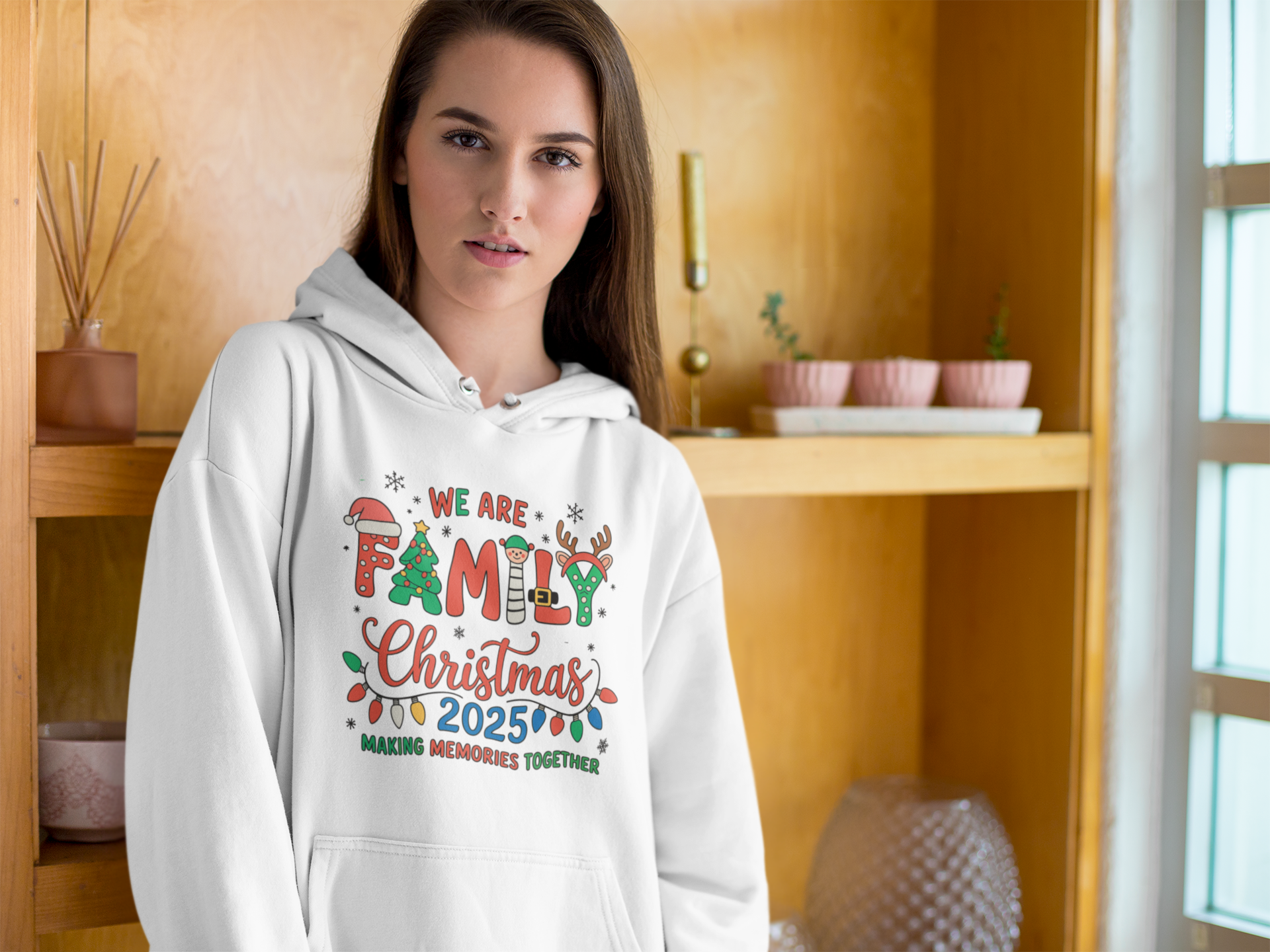 Person wearing a white hoodie with Christmas-themed text in a kitchen setting