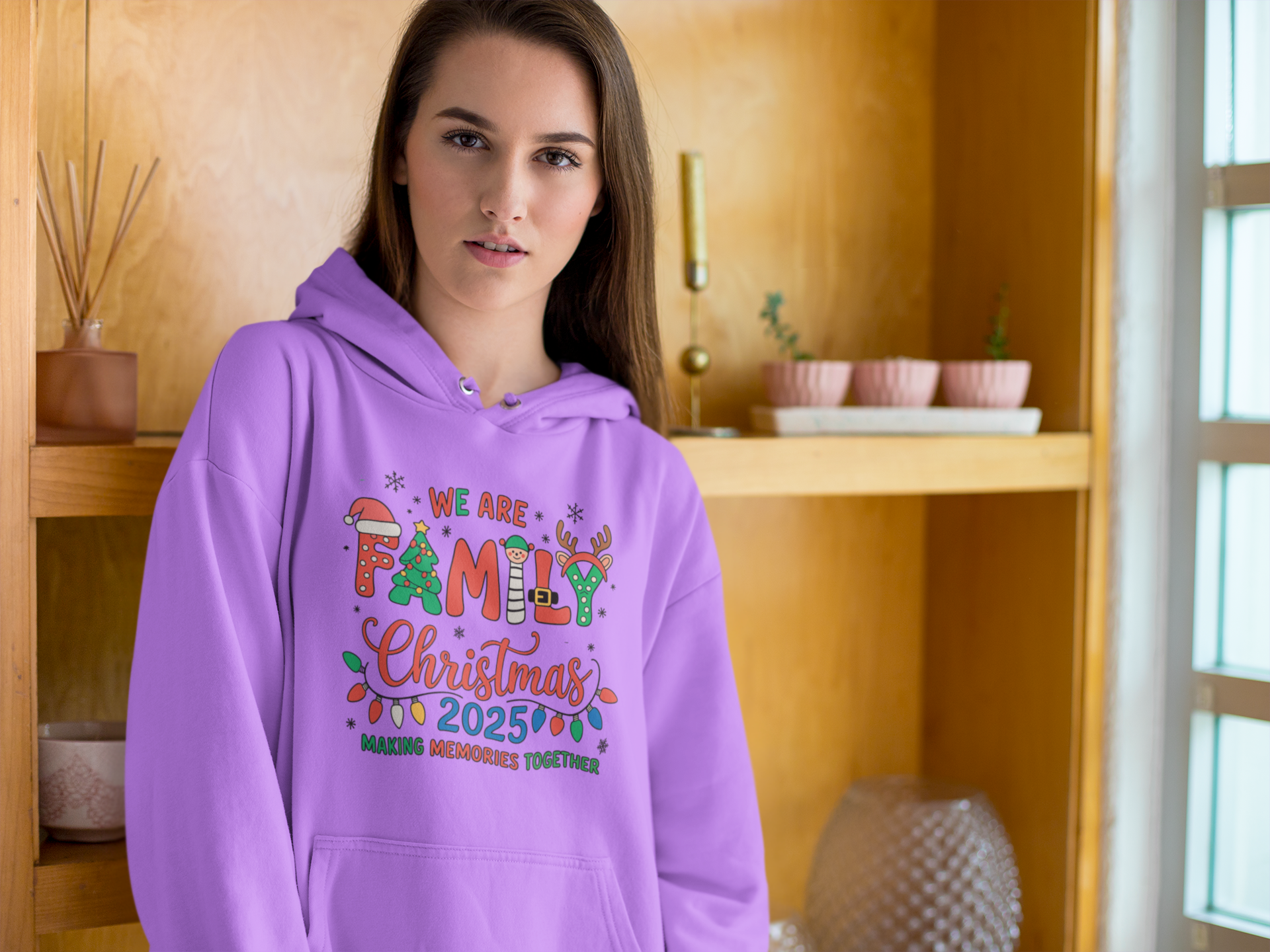 Person wearing a purple hoodie with festive text design indoors.