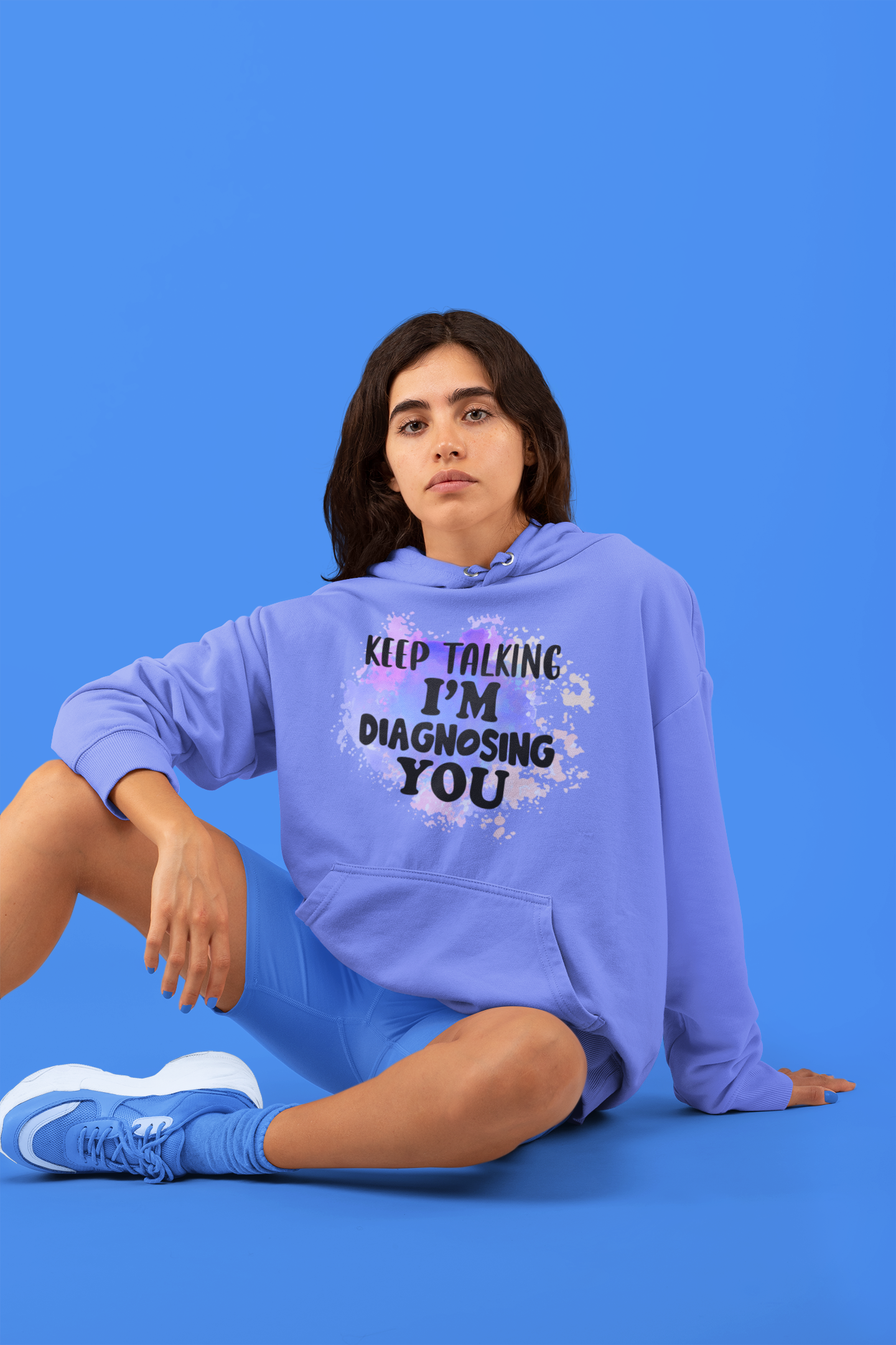 Person wearing a purple hoodie with text and graphics on a blue background