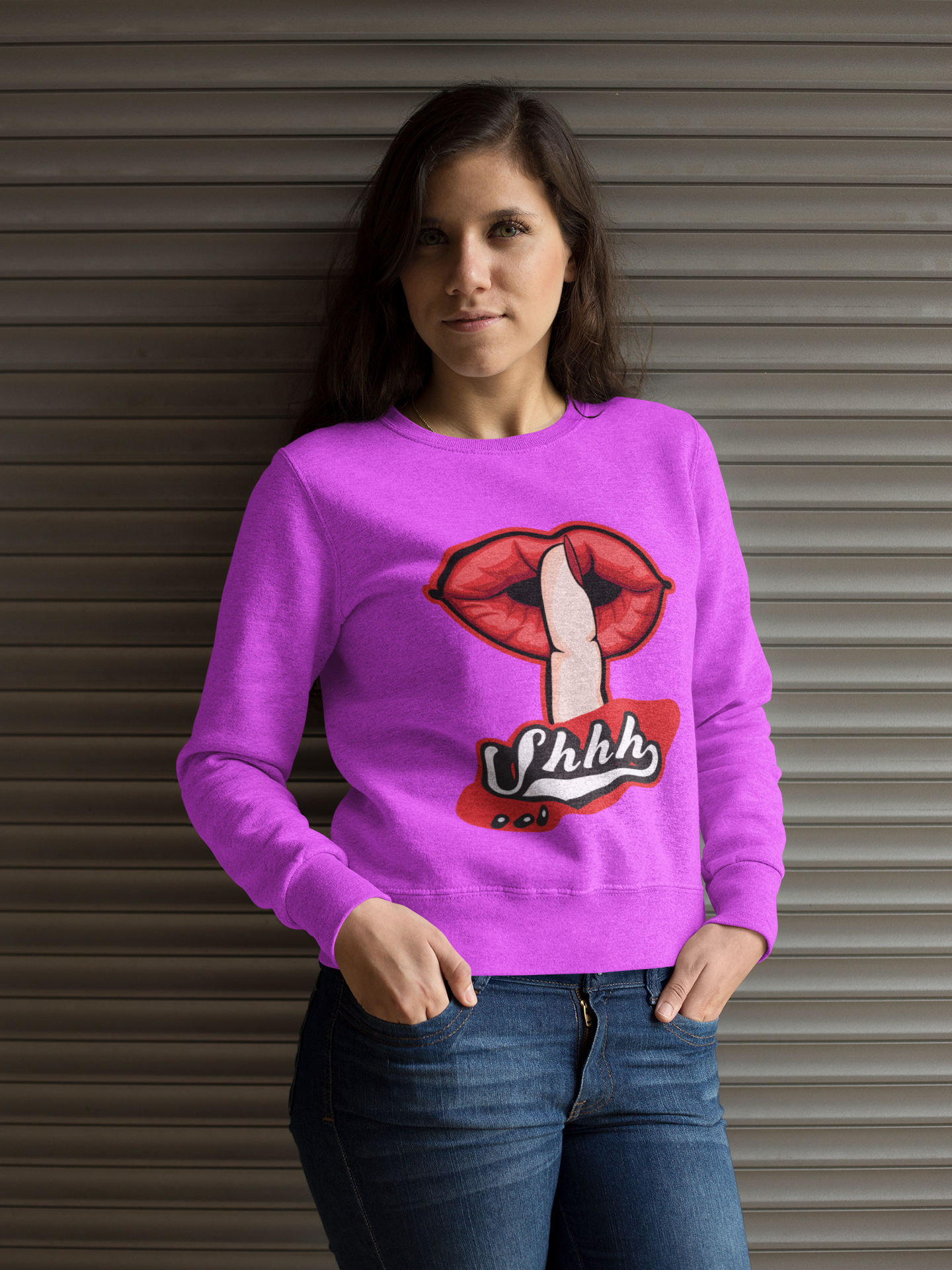 Woman wearing a pink sweatshirt with a graphic design in front of a metallic shutter.