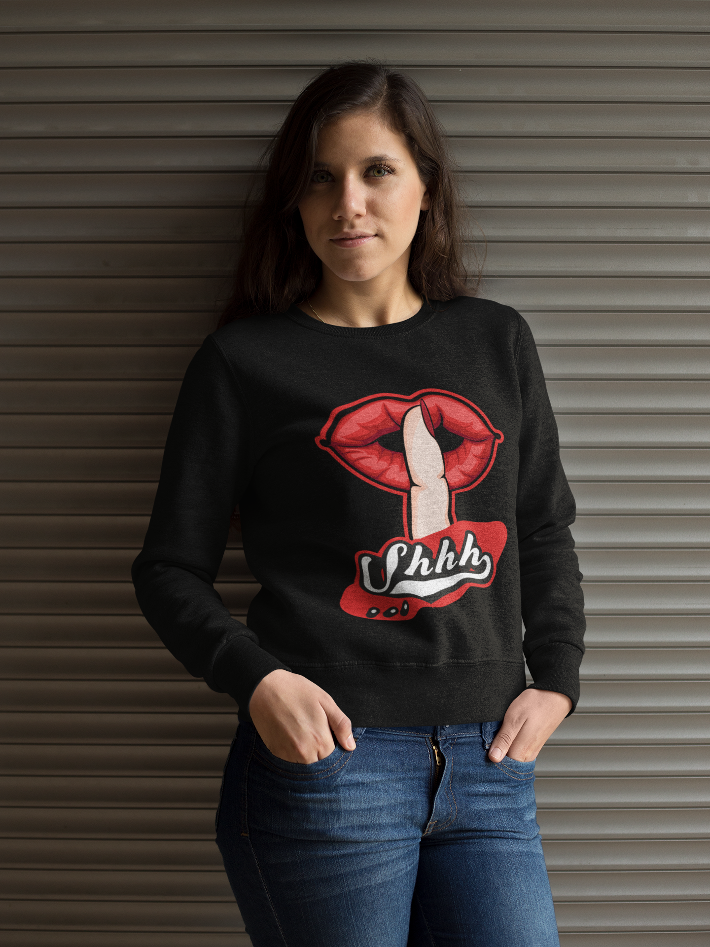Woman wearing a black sweatshirt with a graphic design in front of a metallic shutter.