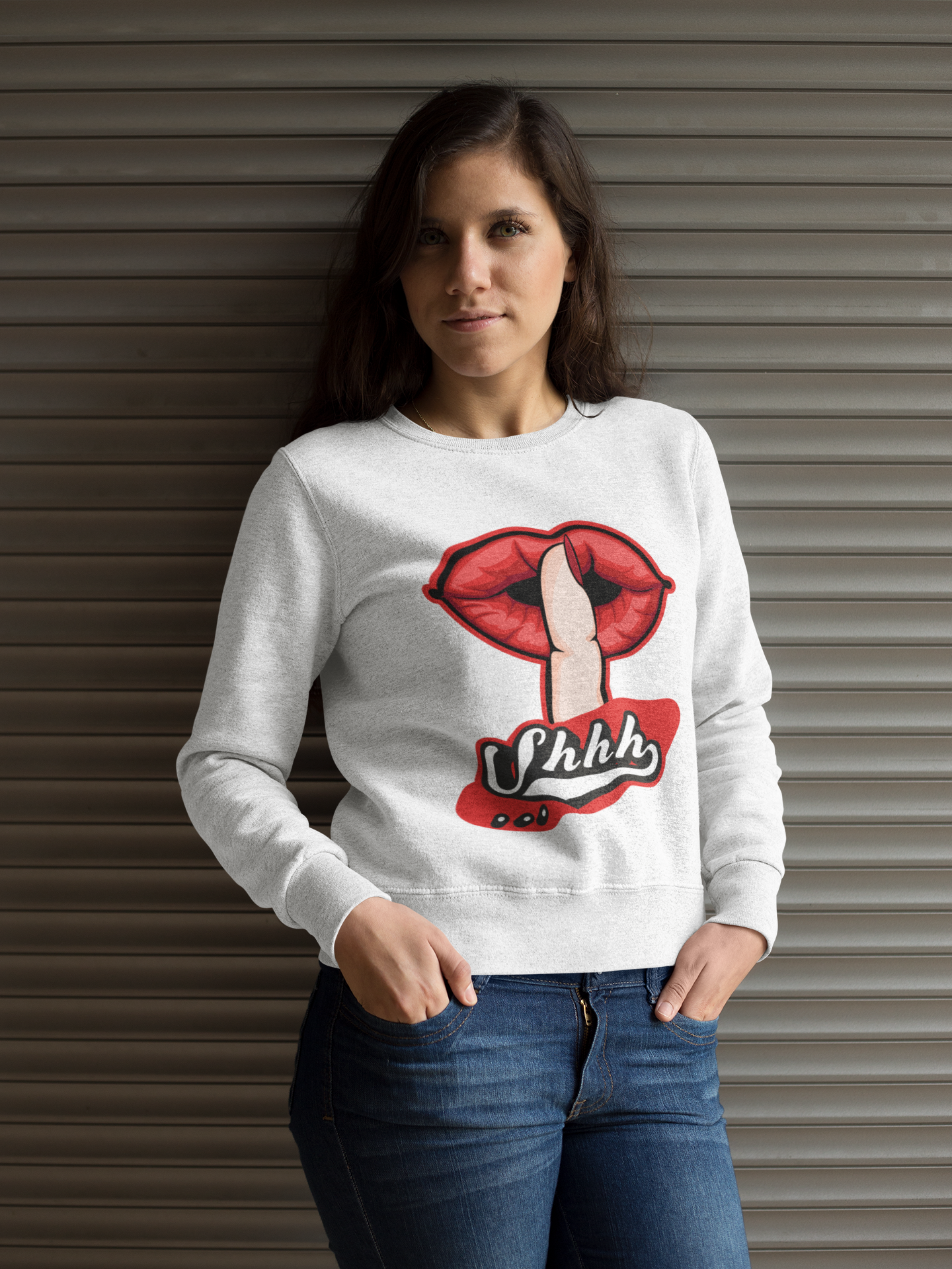Woman wearing a white sweatshirt with a graphic design of red lips and text, standing against a metallic background.