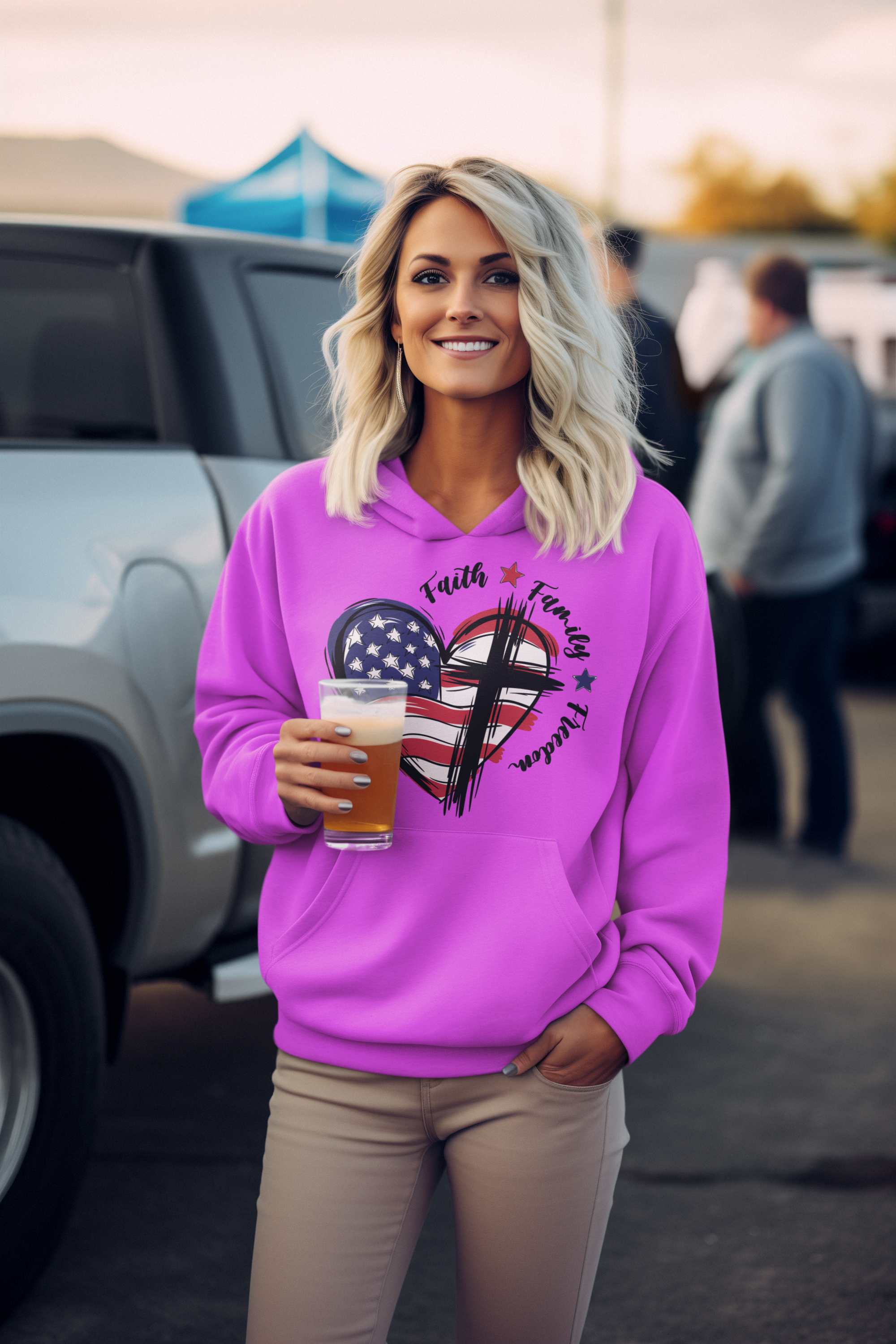 Woman wearing a pink hoodie with a graphic design, holding a drink, standing outdoors.