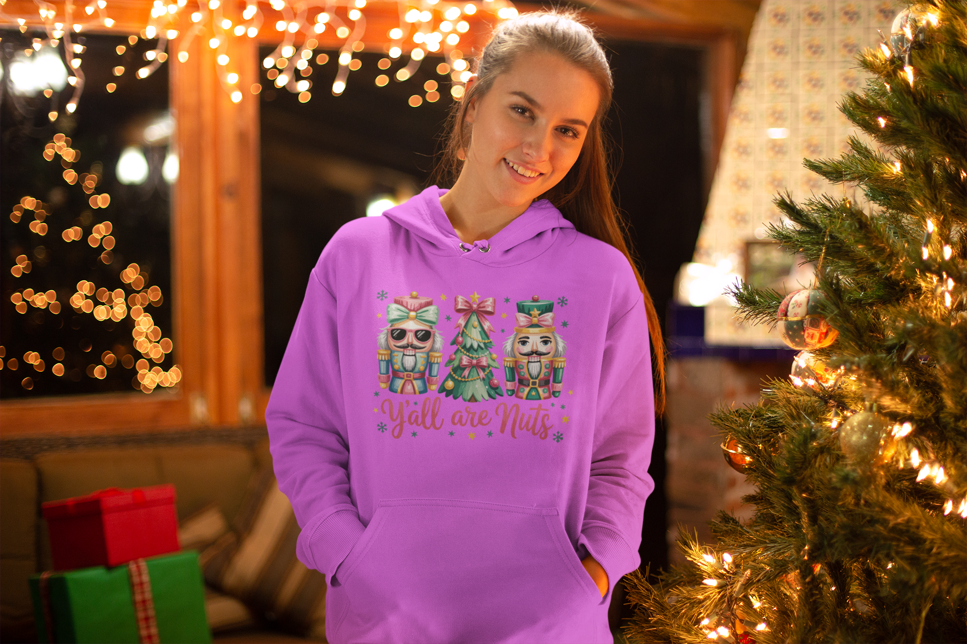 Person wearing a pink hoodie with Christmas-themed designs in a festive setting.