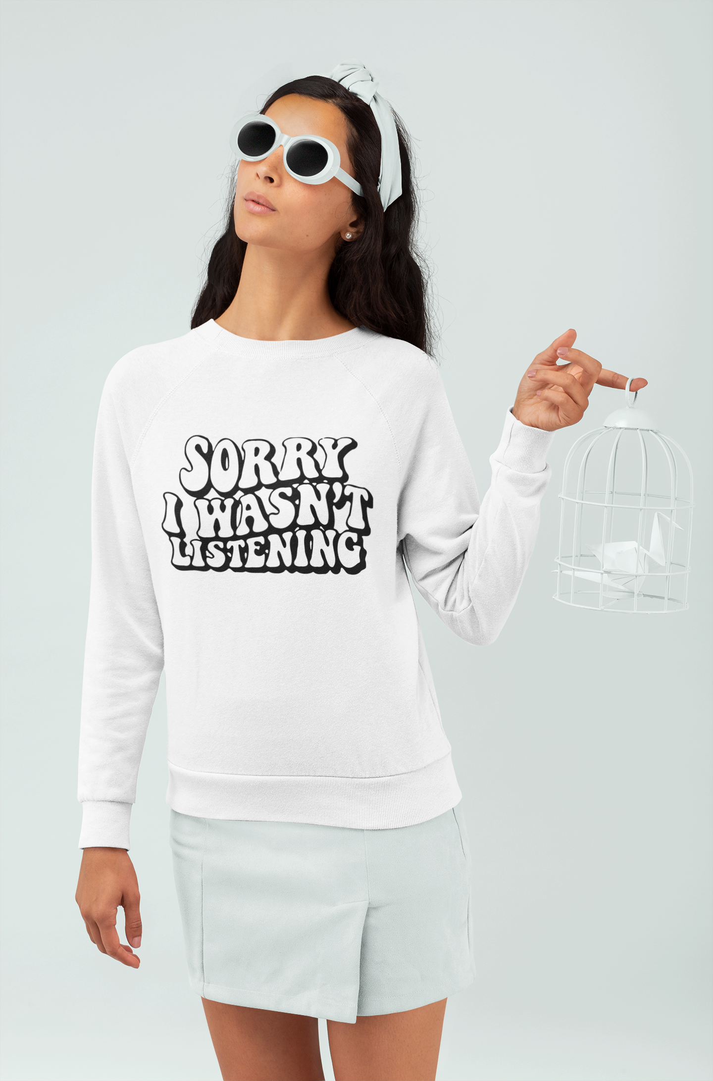 Person wearing a white sweatshirt with 'SORRY I HASN'T LISTENING' text on a plain background