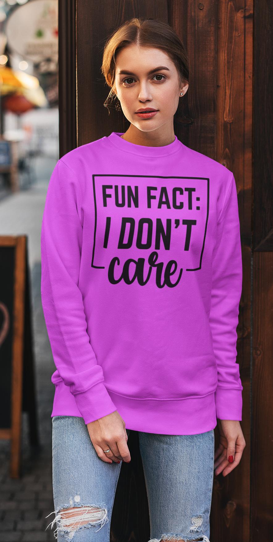 Person wearing a bright pink sweatshirt with text, standing outdoors.