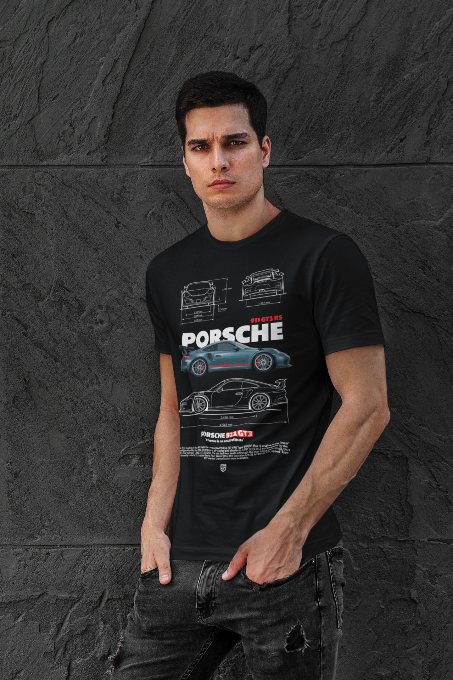 Man wearing a black t-shirt with Porsche car designs against a dark stone wall.