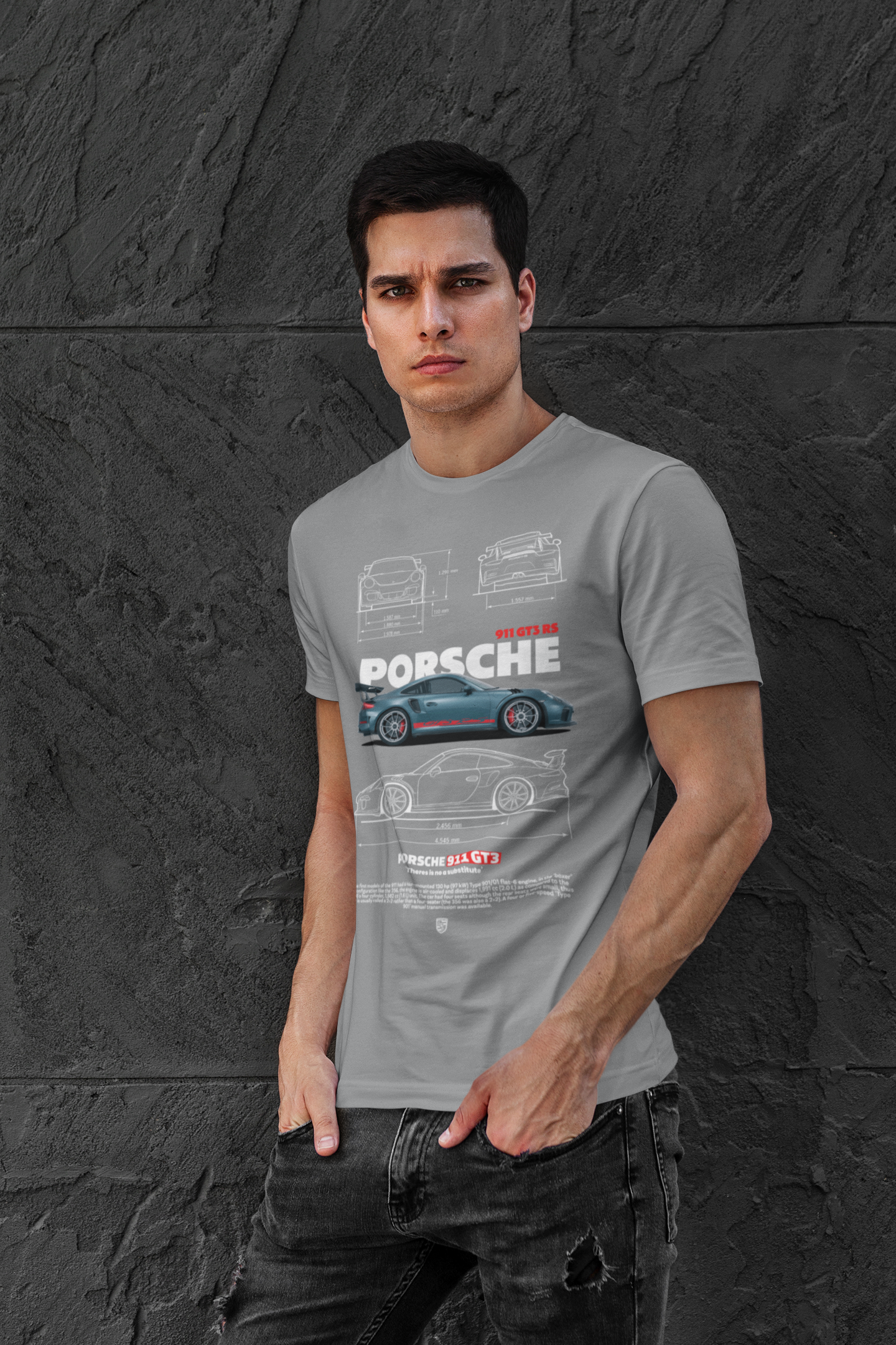 Man wearing a gray t-shirt with Porsche logo and car illustrations against a dark textured wall.