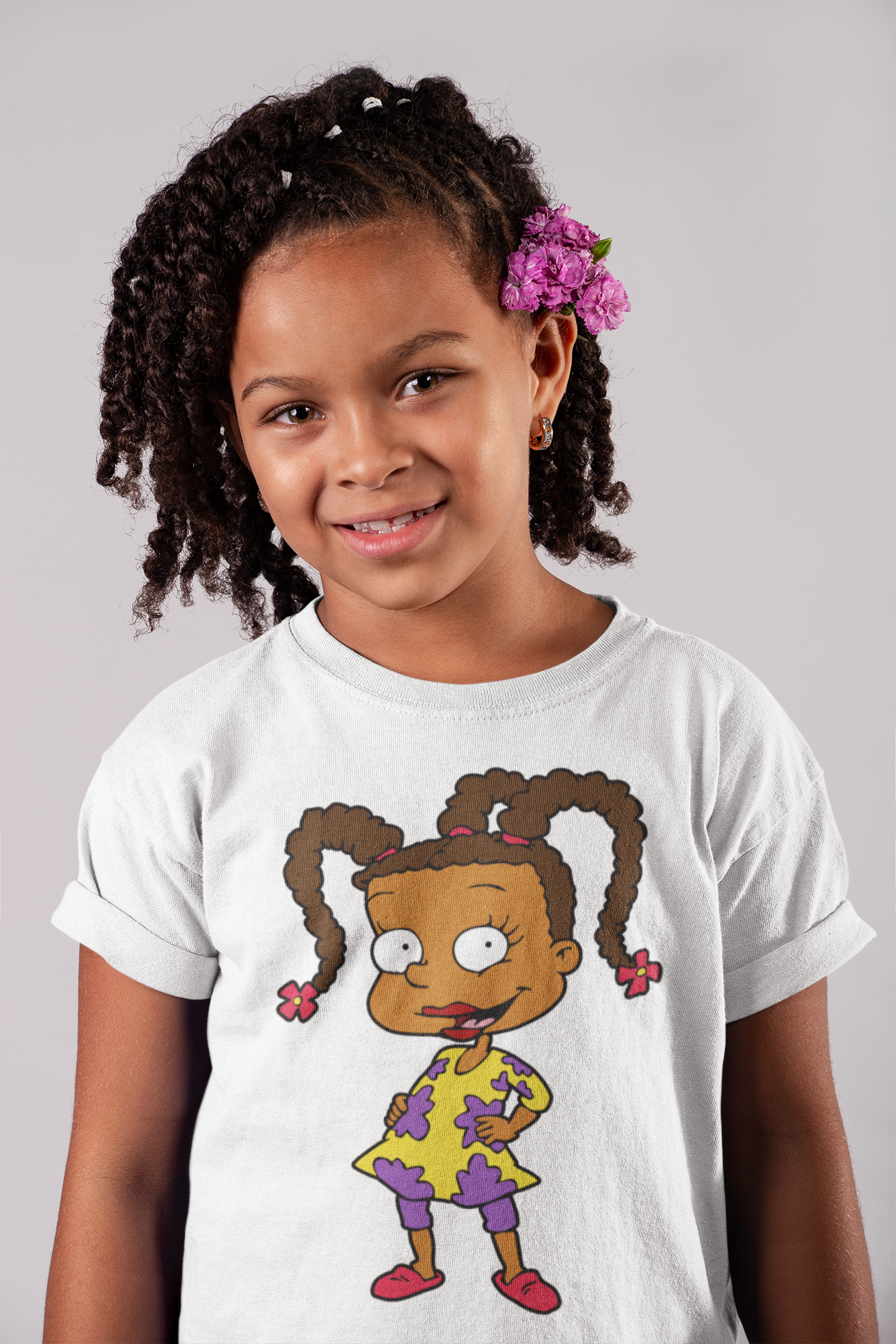 Young girl wearing a white t-shirt with a cartoon character design on a plain background