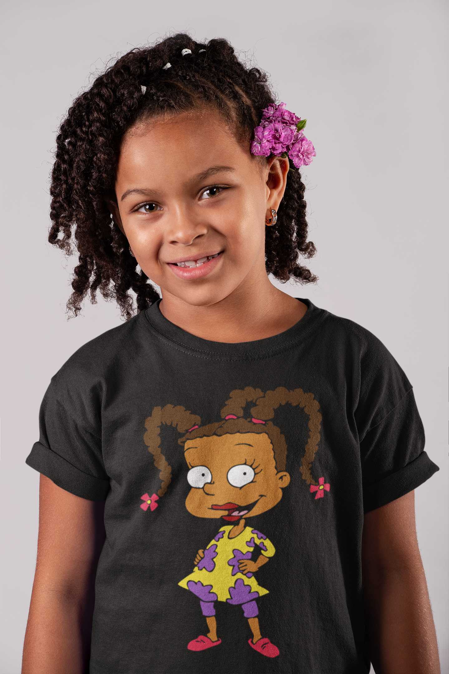 Young girl wearing a black t-shirt with a cartoon character design on a plain background