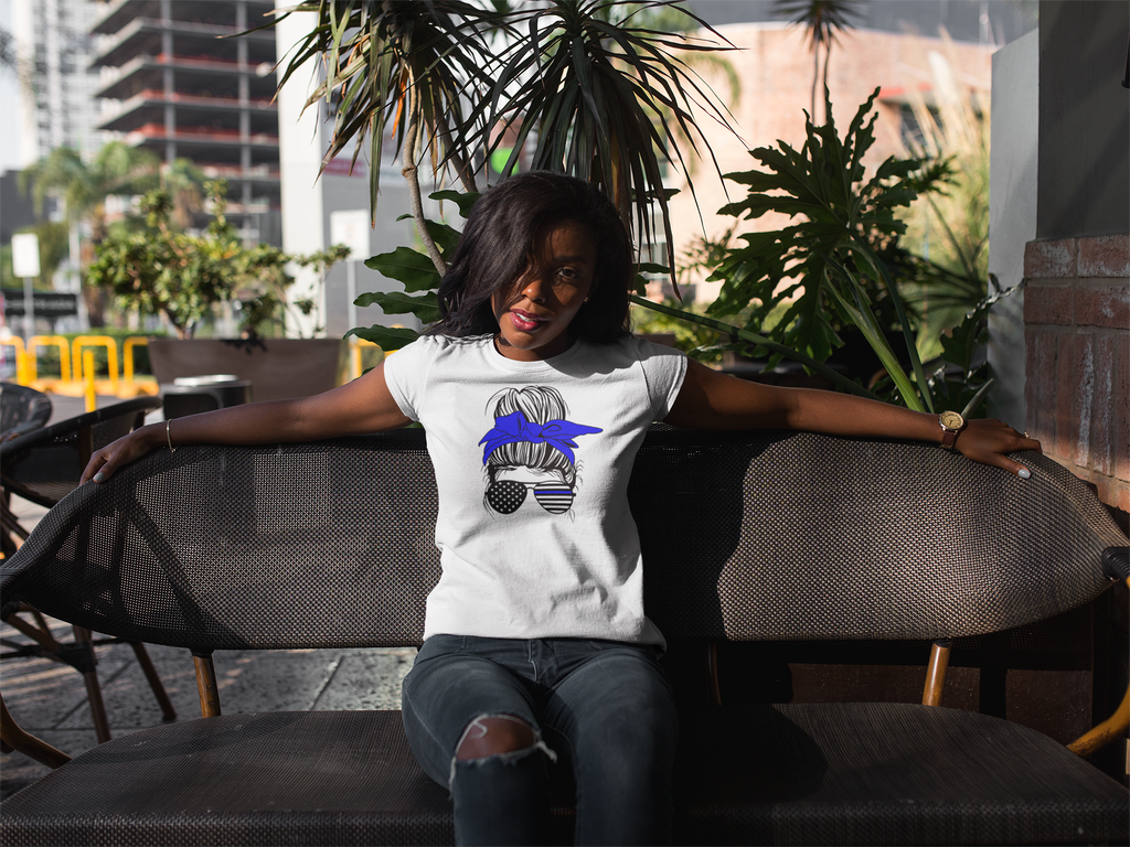 Woman wearing a white t-shirt with a graphic design, sitting outdoors.